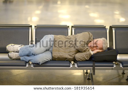 Senior man in airport sleeping on a bench