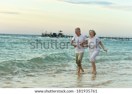 Amusing elderly couple went to the beach to have a walk by sea
