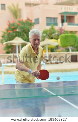 Elderly man playing ping pong at hotel yard