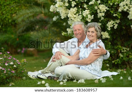 Happy elder couple resting on grass at nature