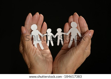 Paper family in hands isolated on black background