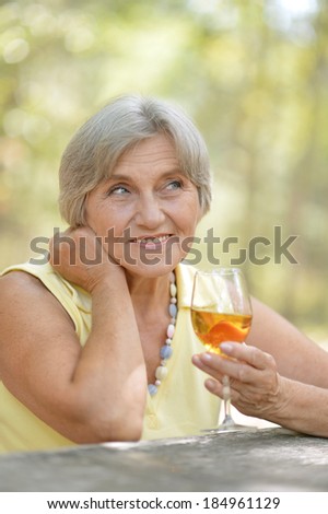 Portrait of happy nice old woman drinking wine