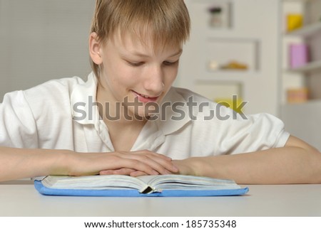 Cute smiling boy reading a book with interest