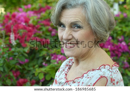 Close-up portrait of an older woman on walk with pink flowers