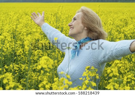 Beautiful old woman went out for a walk in yellow field