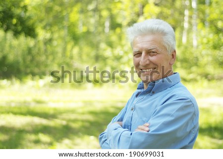Portrait of an elderly man walking in the forest in summer