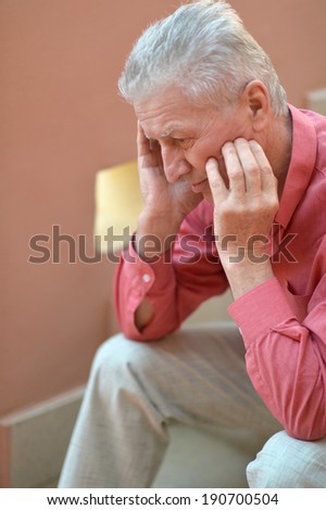 Portrait of a cute old thoughtful man on red wall background