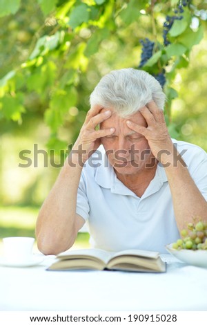 Handsome older man sitting at a table at home on the veranda