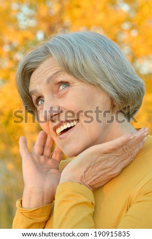 Nice smiling old woman on the yellow leaves background