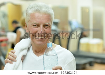 Elderly man in a gym. drinking water after exercise