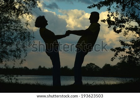 Silhouette of an elderly couple in love at night river