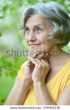 Nice elderly woman resting in summer park