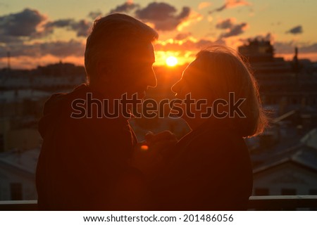 Silhouettes of elderly couple in love over sunset sky