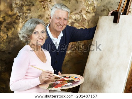 Portrait of beautiful elderly couple painting with easel