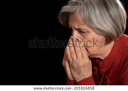 old woman in red crying on a black background