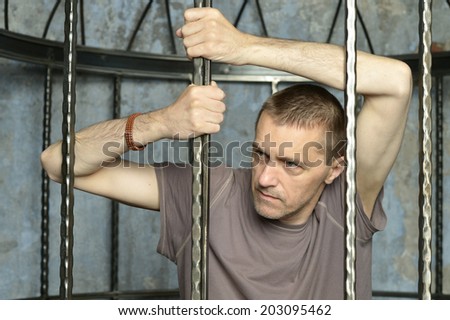 Man in cage with hands on steel lattice
