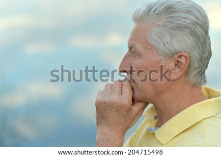Portrait of thoughtful old man on sky background
