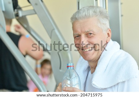 Elderly man in a gym. drinking water after exercise