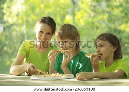Happy cute family eat pizza together outdoors
