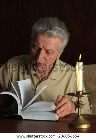 Elderly thoughtful man with book against a dark background