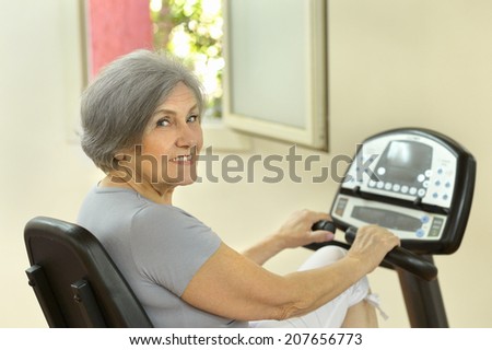 Cute smiling senior woman exercising in gym