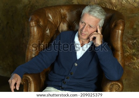 Portrait of mature thoughtful man sitting in armchair