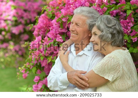 Happy elder couple on pink flowers background