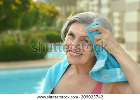 Smiling senior woman at pool with towel
