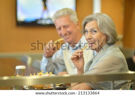 Beautiful mature couple eating french fries in cafe