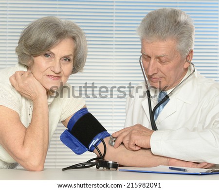 Elderly doctor measuring blood pressure to the senior woman