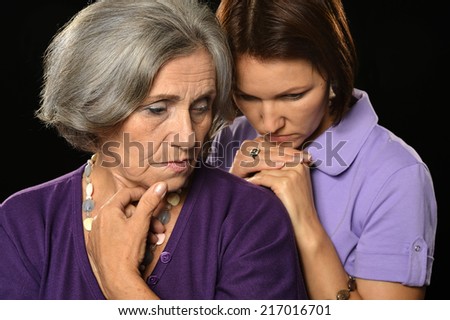 Sad mother and daughter on a black background