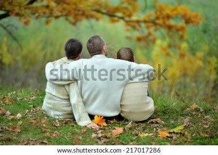 Family sitting in autumn park,back view