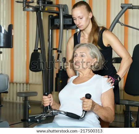 Senior woman exercising in gym with sport coach
