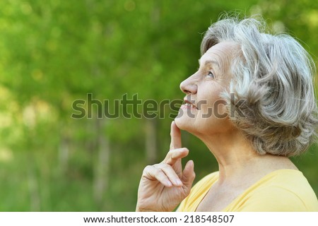 Nice smiling old woman on the green leaves background