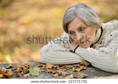 Cute elderly woman walking in the park in September