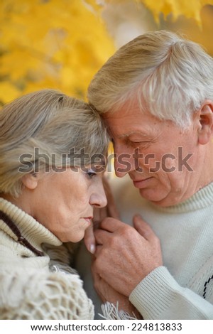 Sad senior couple standing in autumn park
