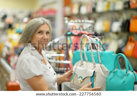 Smiling old lady choosing dress in store