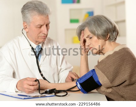 Elderly doctor measuring blood pressure of the senior woman