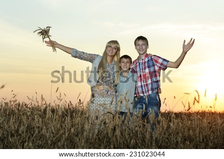 Portrait of happy family hugs in field in sunset