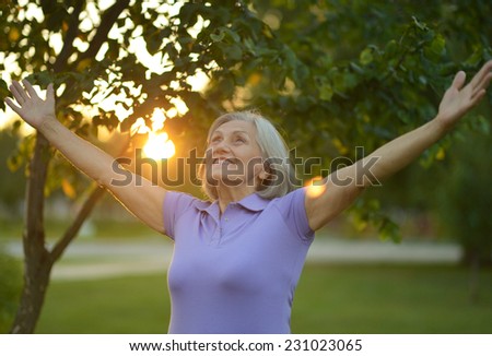 Woman stretching her hands up at sunset