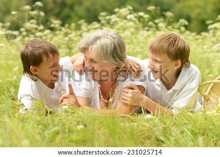 Grandmother with her grandchildren resting on green grass
