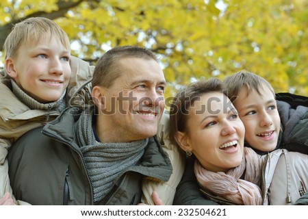 Portrait of a beautiful happy family sitting in autumn park,man showing something by hand