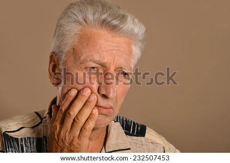 Portrait of a sad old man on a brown background