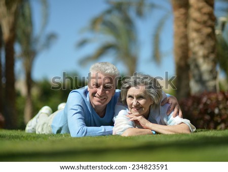 Happy elder couple resting on grass on nature