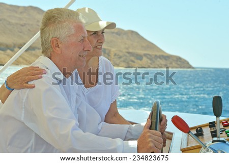 Amusing elderly couple have a ride in a boat on sea