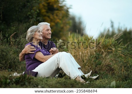 Happy elderly couple sitting on grass in park