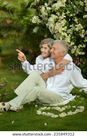 Happy elder couple resting on grass on nature