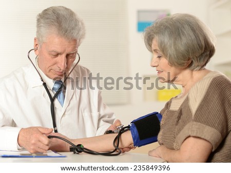 Elderly doctor measuring blood pressure to the senior woman