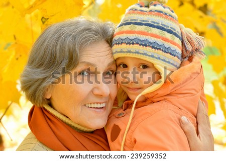 Grandmother with her granddaughter for a walk during the fall of the leaves in the park
