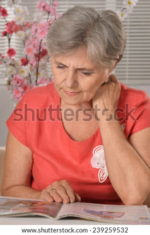 Portrait of an attractive middle-aged woman in a red dress reading magazine